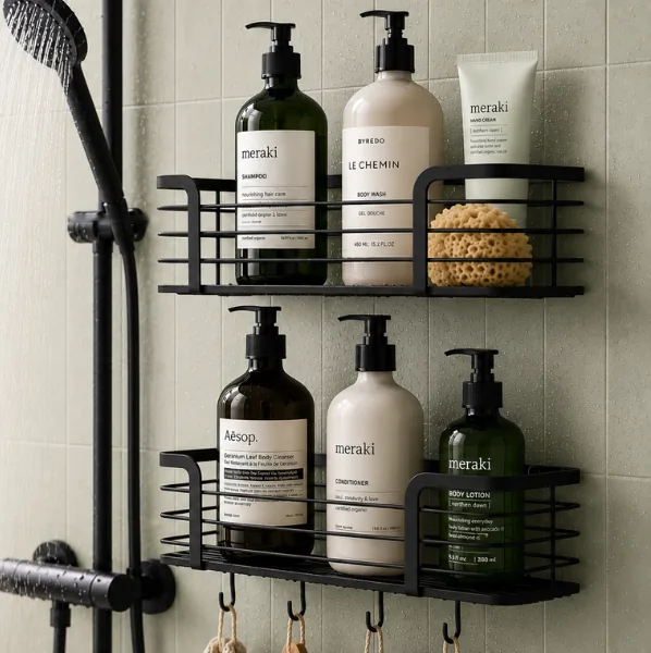 Two black Prana shower caddies holding shampoo, conditioner, body wash and a sponge on a pale tiled shower wall beside a black shower rail